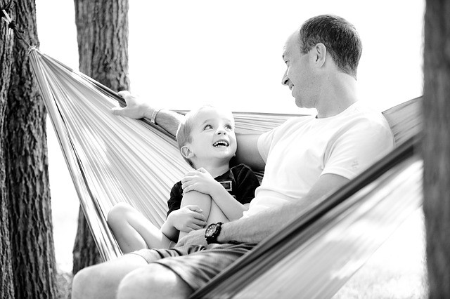 A father looking lovingly at his son on a hammock