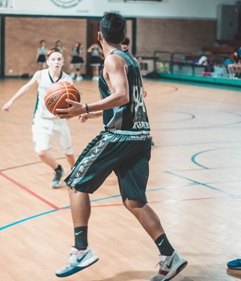 A small boy defending against a taller basketball player