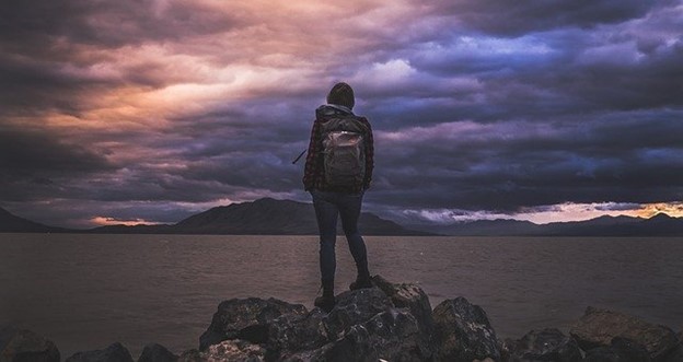 A person looking out on a lake with storm clouds overhead