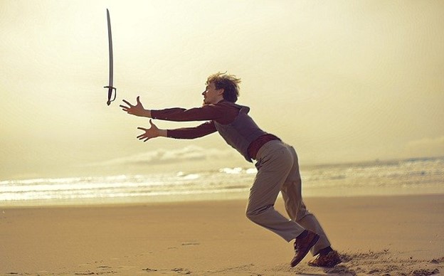 a man chasing after a sword that's spinning through the air