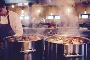 two large, steaming stockpots full of soup