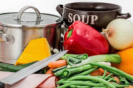 A pile of bulk cooking ingredients in front of two large pots