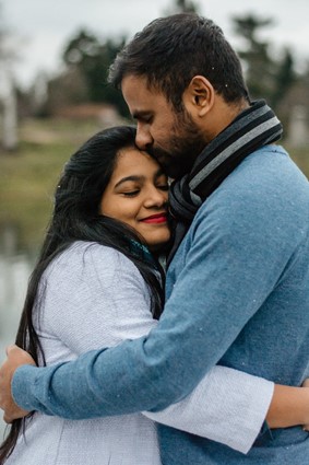 a couple hugging outdoors, looking content