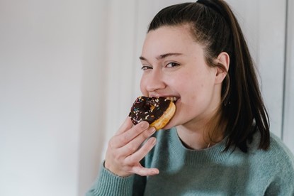 A young woman eating a chocolate donut