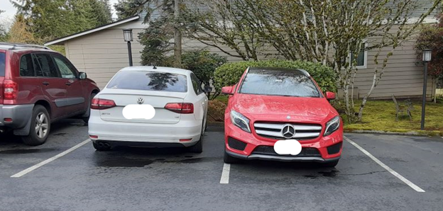 A red car parked poorly too close to a white car