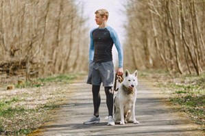 A man walking his dog with earbuds in