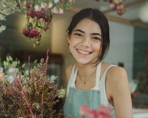 A young woman working in a flower shop, smiling warmly