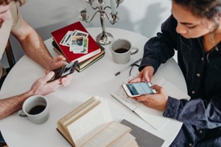 a man and a woman at a table with coffee, facing each other but looking at their phones