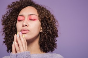 a woman with eyes closed and hands steepled