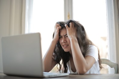 A person looking at a computer while very frustrated