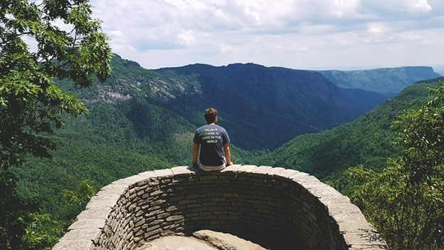 A man sitting at a mountaintop thinking about life