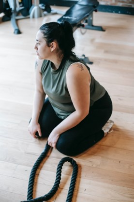 A woman at a cross-fit gym pausing between exercises to figure out what to do next.