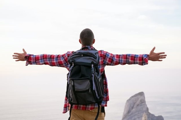 a man standing before a foggy ocean with arms wide open