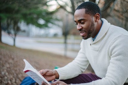 A man reading a book of wisdom in a park