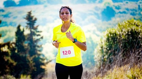 A woman looking tired and sweaty while running a race