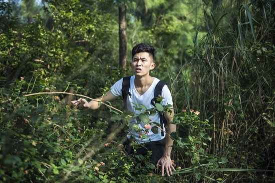 a young man looking lost bushwhacking through the forest