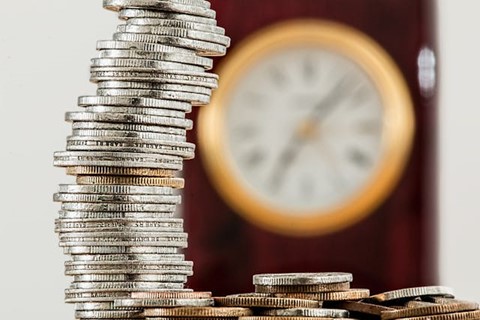 A stack of change with a clock in the background