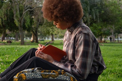 A young woman journaling on a lawn.