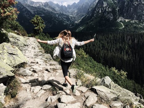 A woman happily hiking down a path