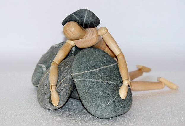 a wooden figure of a person collapsed on a pile of stones