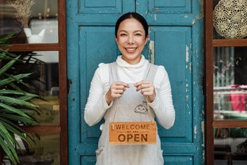 A small business owner holding an open sign