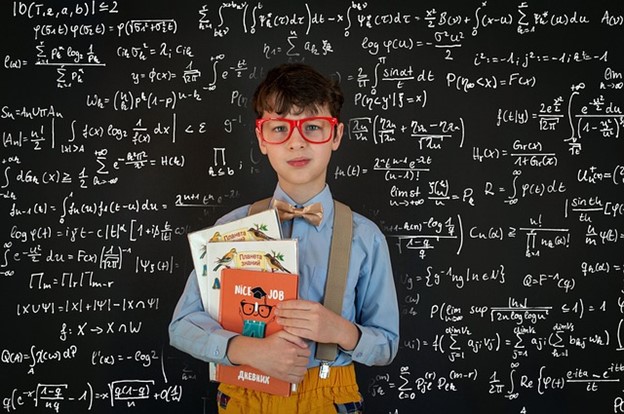 a nerdy boy in front of a blackboard looking smart