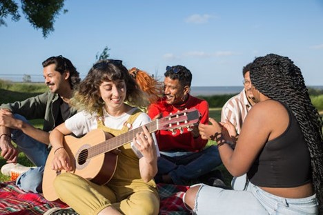 a group of friends outside; one is playing guitar