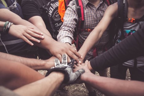 a group of hikers with their hands together in a circle