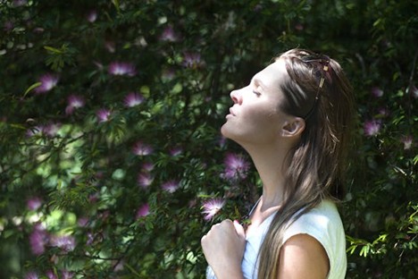 a woman pausing to smell some flowers