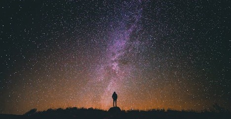 a silhouette of a person against the Milky Way