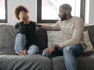 a man apologizing to his partner on the couch