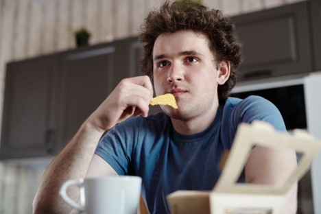 A man eating chips out of habit