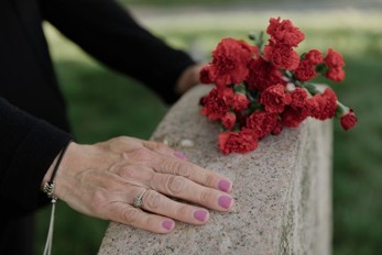 a woman putting flowers on a grave