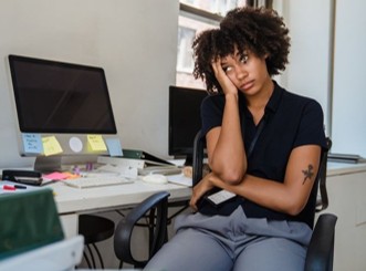 a woman struggling to focus on her work at her desk
